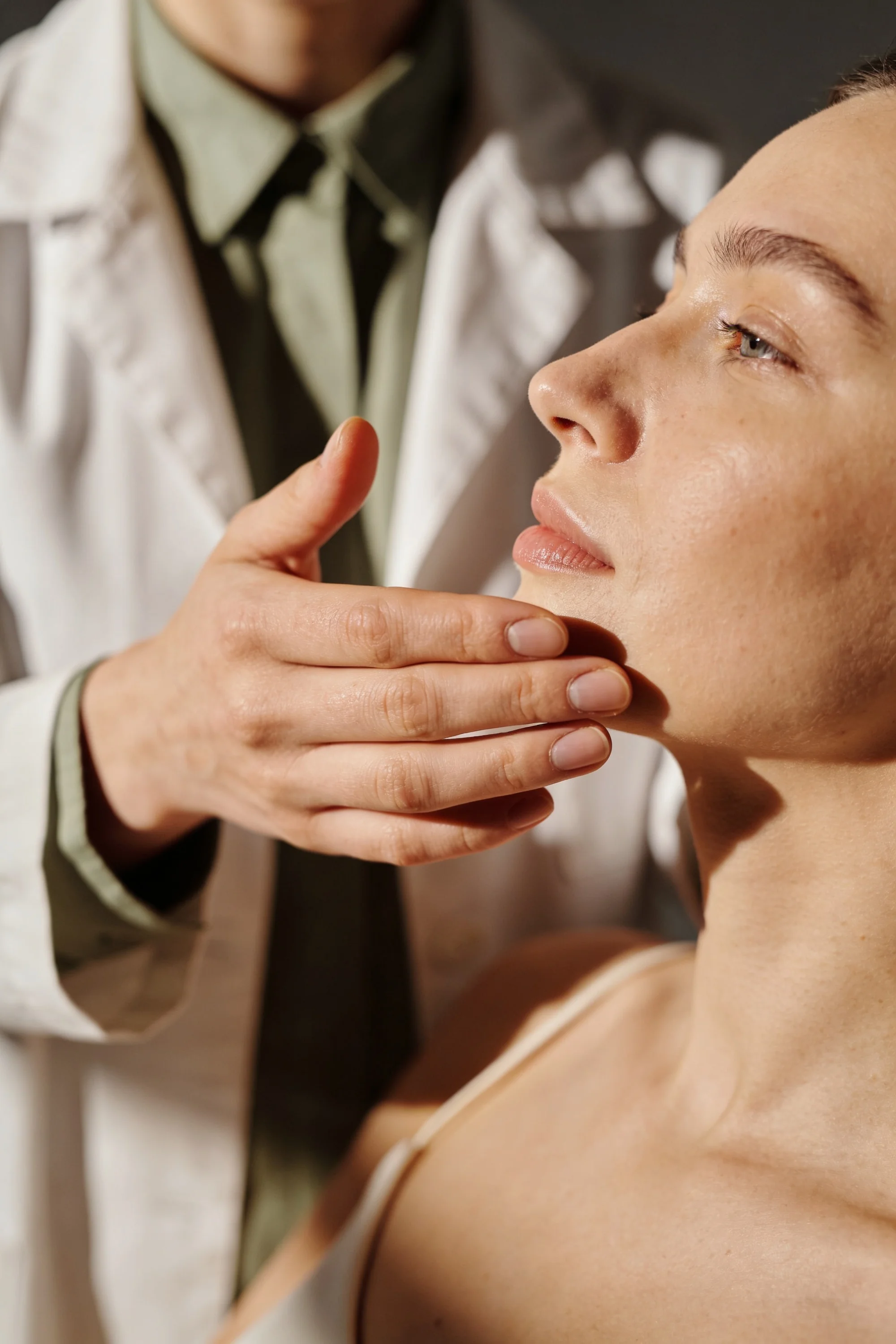 Clinician examining a patient's face during a dermatology consultation — Experience Design by Parallel Creative Agency — Derma, health