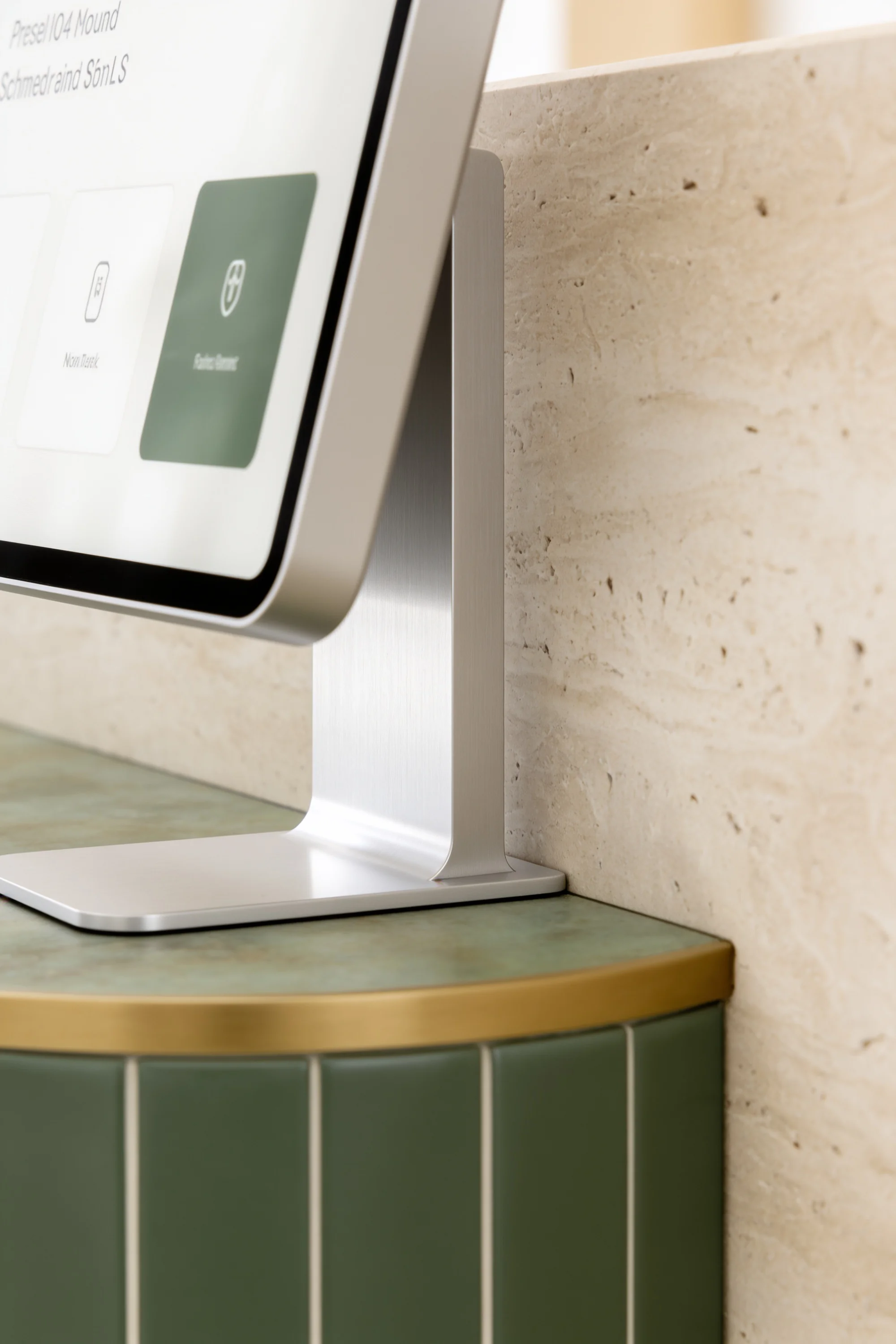 Digital patient check-in screen set into a green-tiled and stone reception counter — Digital Design by Parallel Creative Agency — Derma, health