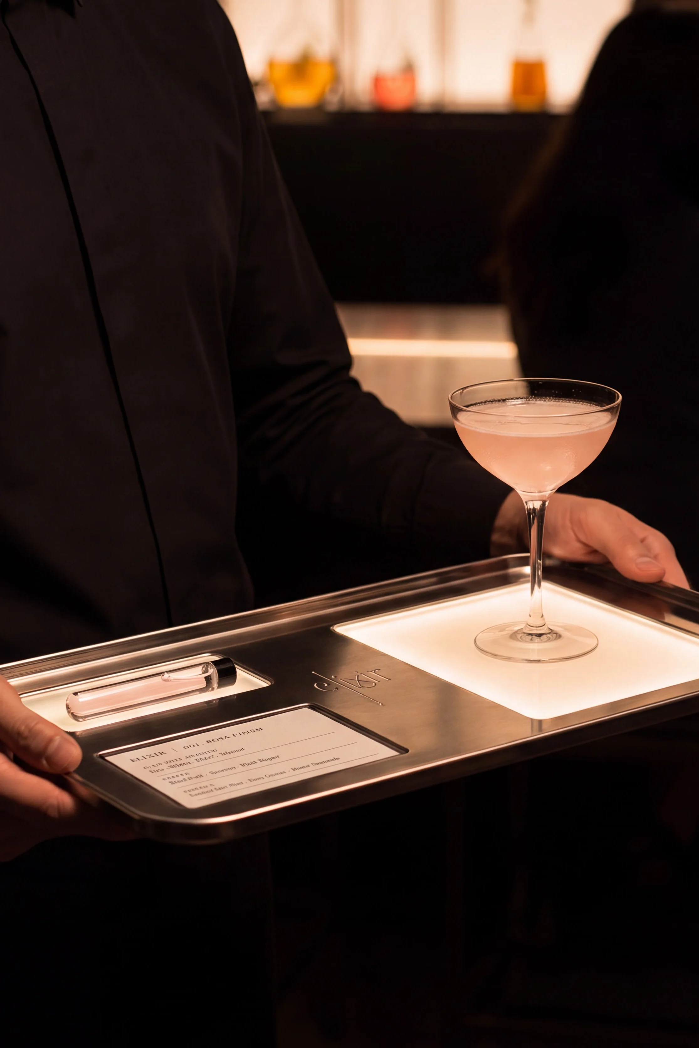 Server holding an illuminated cocktail tray with a drink and personalised information card — Experience Design by Parallel Creative Agency — Elixir, hospitality