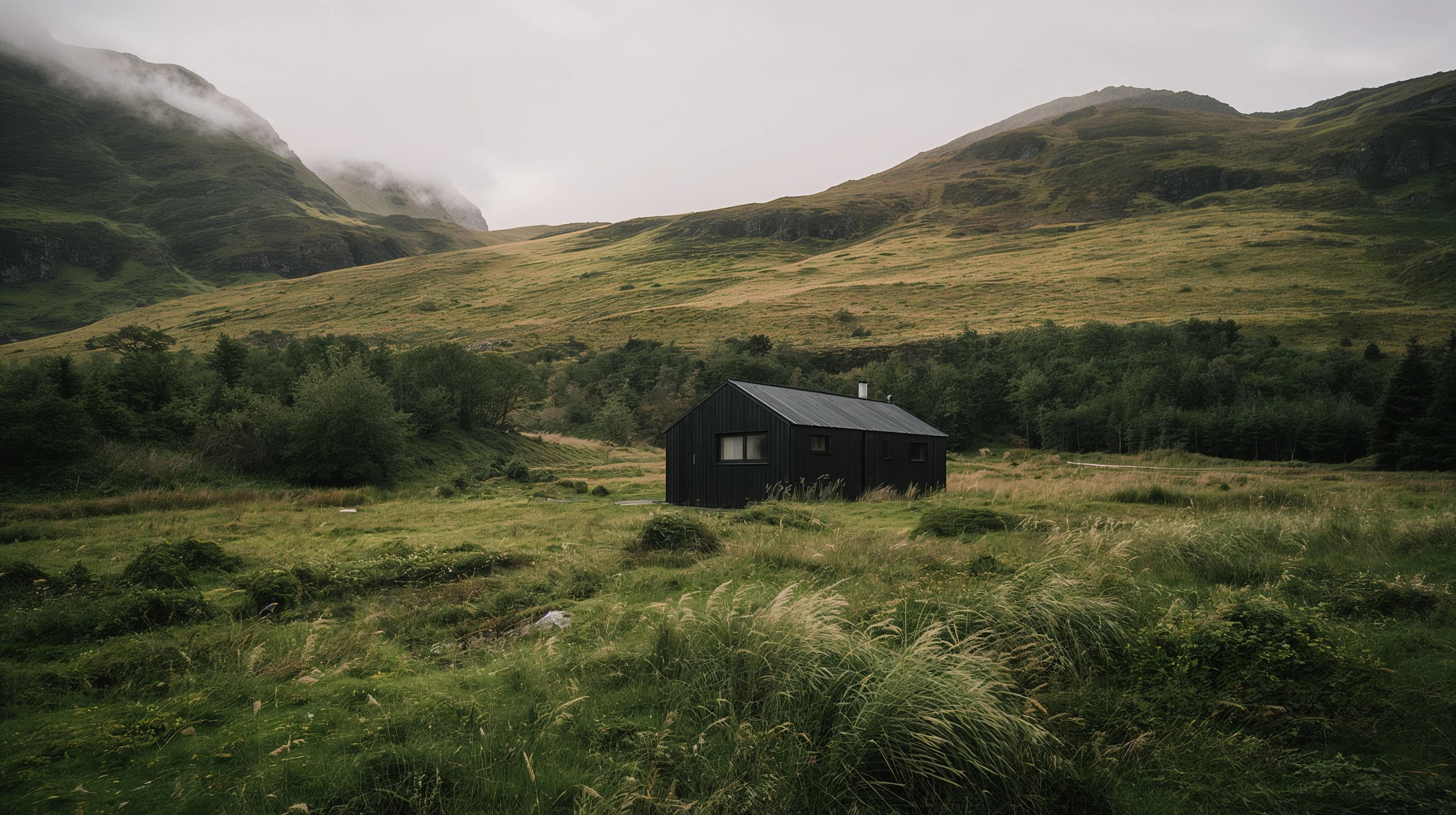 Remote black cabin in a cloud-covered mountain valley, conceived for tech hotel stays in wild landscapes — Spatial Design by Parallel Creative Agency — Kabin