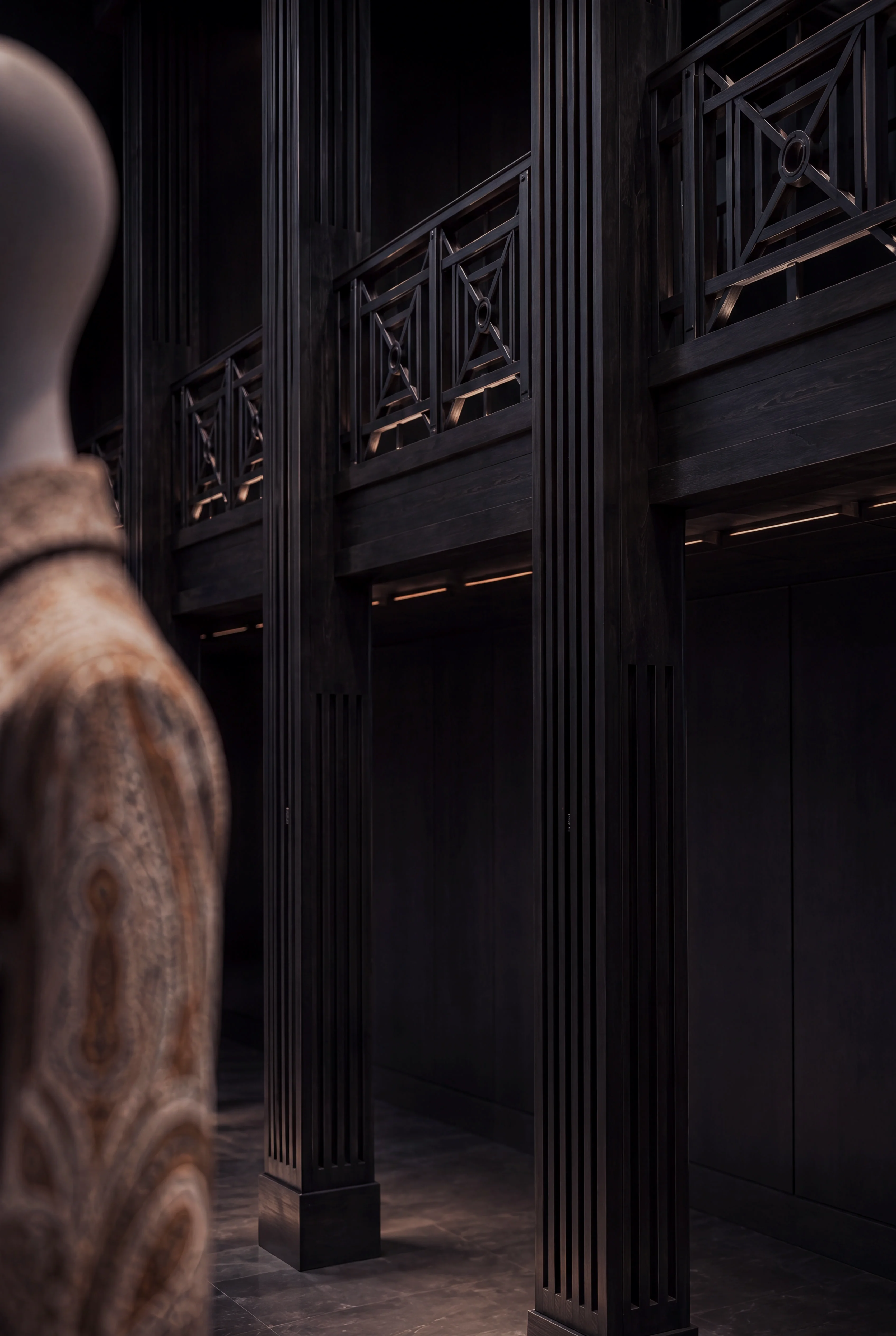 Detail of the dark timber gallery architecture beside a patterned exhibition garment — Interiors by Parallel Creative Agency — Loom, culture